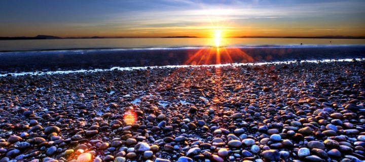 Das Beach Pebbles In Sun Lights At Sunrise Wallpaper 720x320