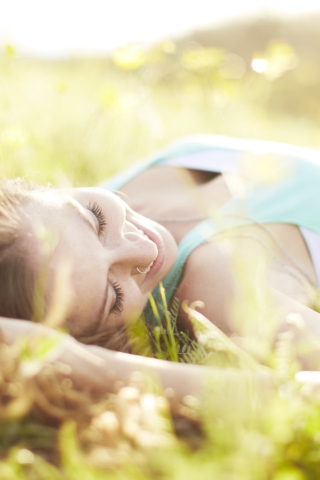 Sfondi Happy Girl Lying In Grass In Sunlight 320x480