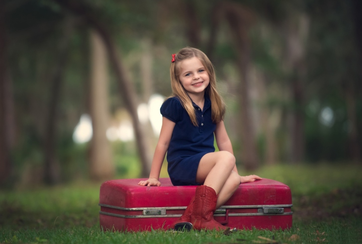 Sfondi Little Girl Sitting On Red Suitcase