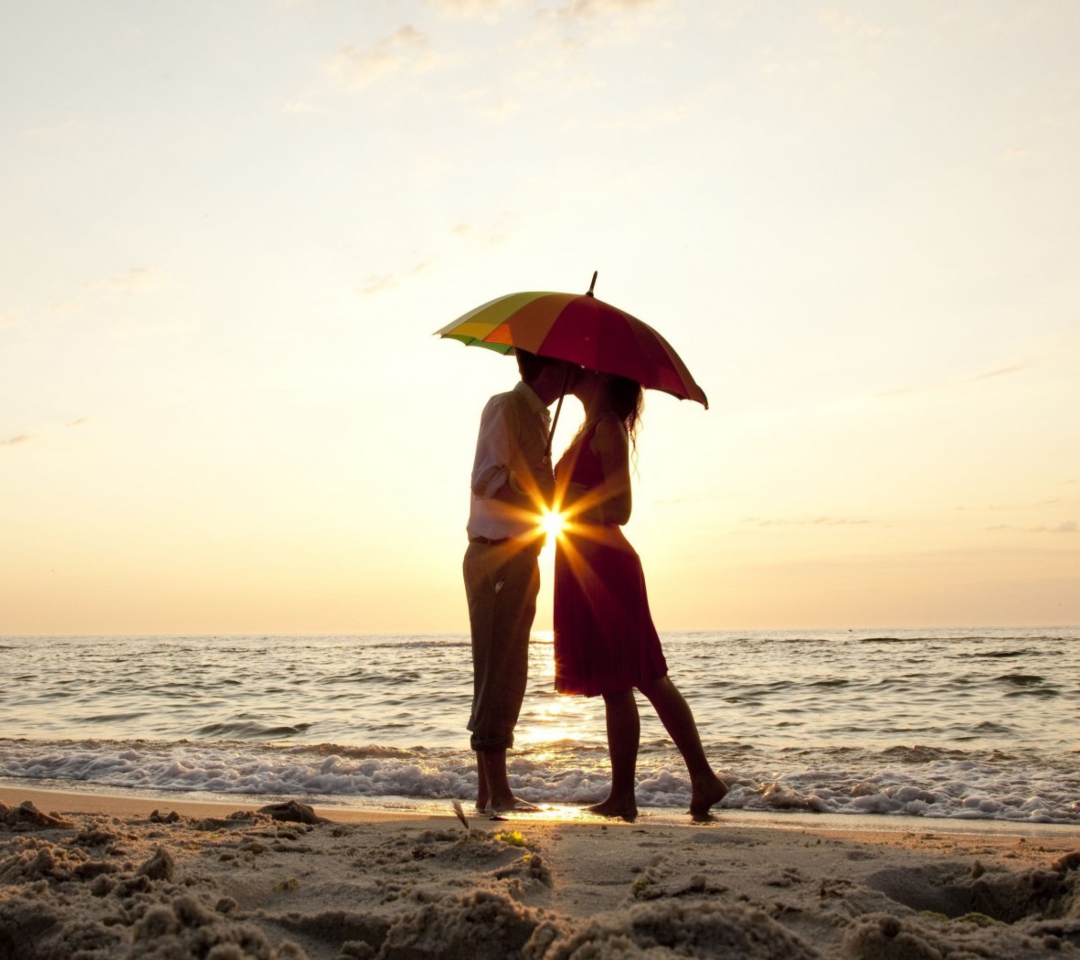 Fondo de pantalla Couple Kissing Under Umbrella At Sunset On Beach 1080x960
