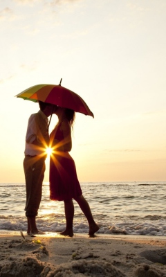 Couple Kissing Under Umbrella At Sunset On Beach wallpaper 240x400