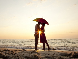 Das Couple Kissing Under Umbrella At Sunset On Beach Wallpaper 320x240