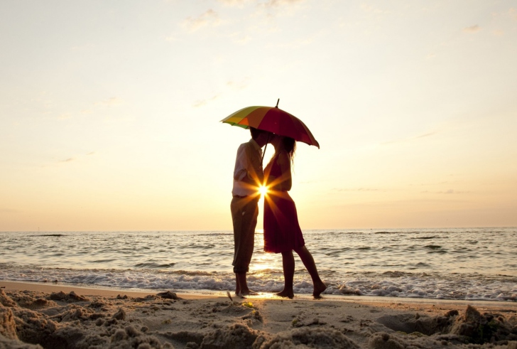 Обои Couple Kissing Under Umbrella At Sunset On Beach