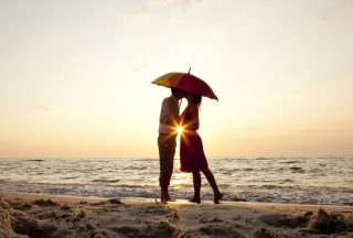 Kostenloses Couple Kissing Under Umbrella At Sunset On Beach Wallpaper für Android, iPhone und iPad