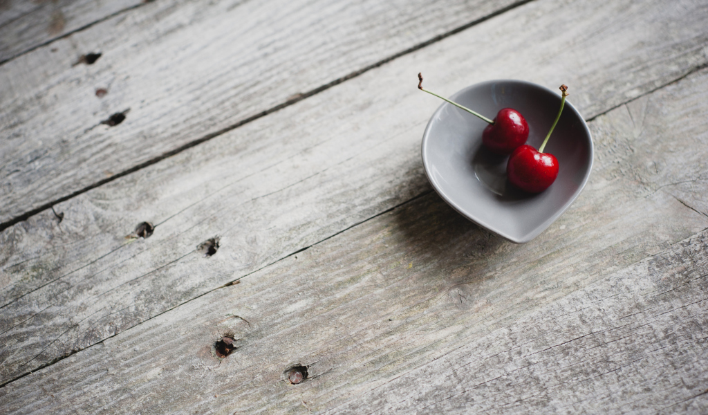 Two Red Cherries On Plate On Wooden Table wallpaper 1024x600