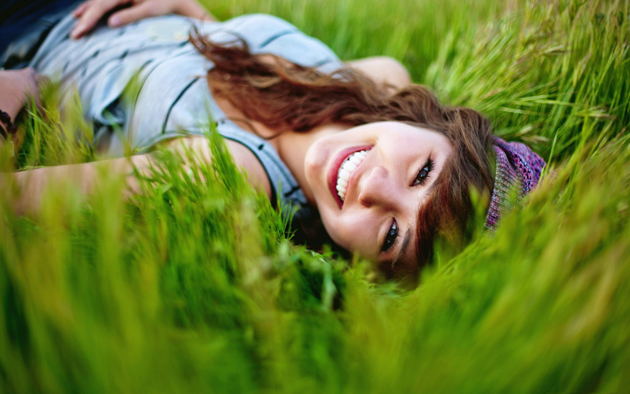Sfondi Smiling Girl Lying In Green Grass 1280x800