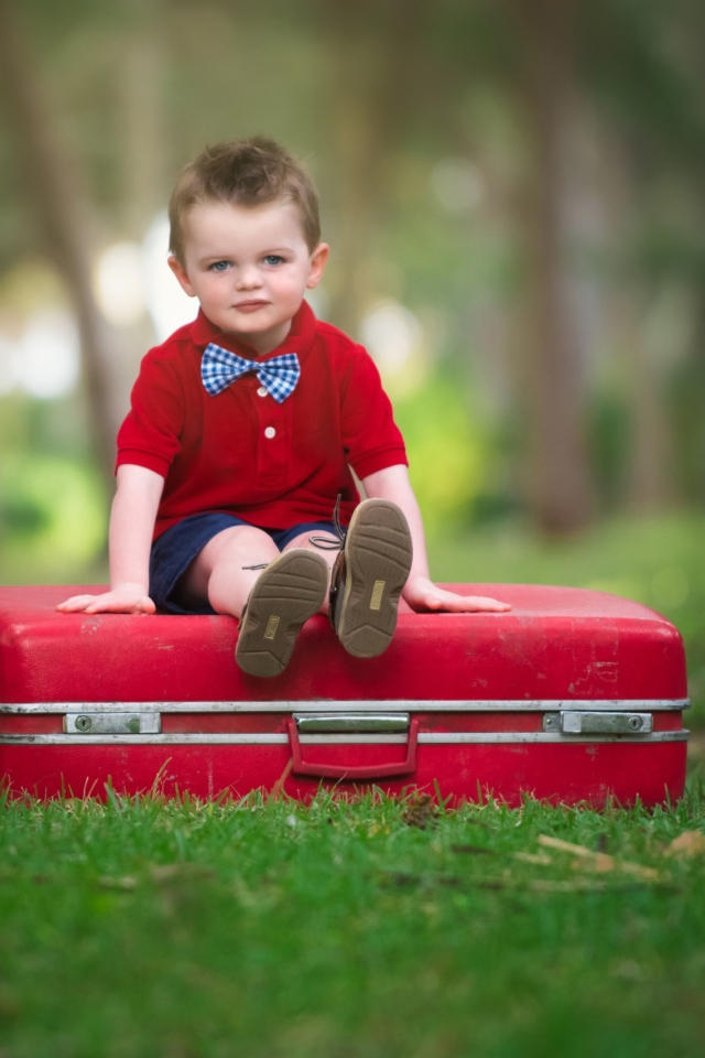 Das Cute Boy Sitting On Red Luggage Wallpaper 640x960