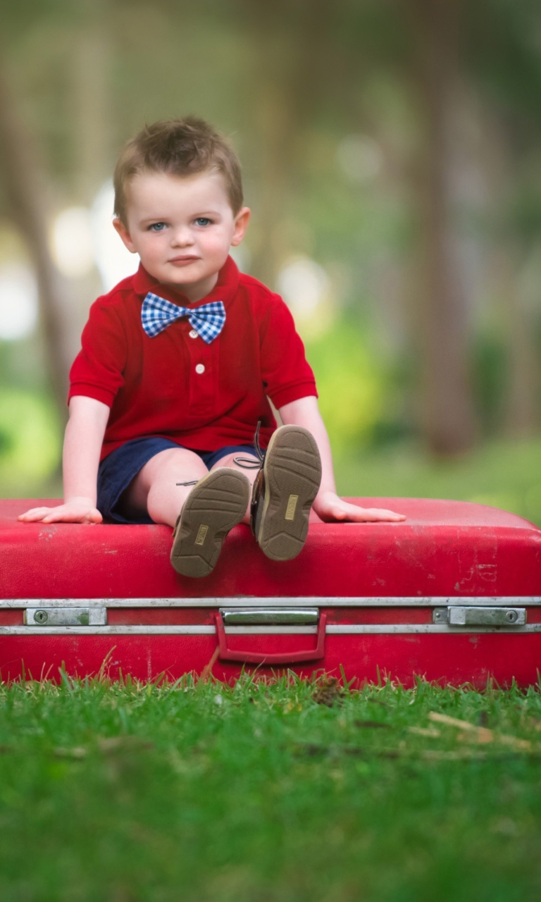 Обои Cute Boy Sitting On Red Luggage 768x1280