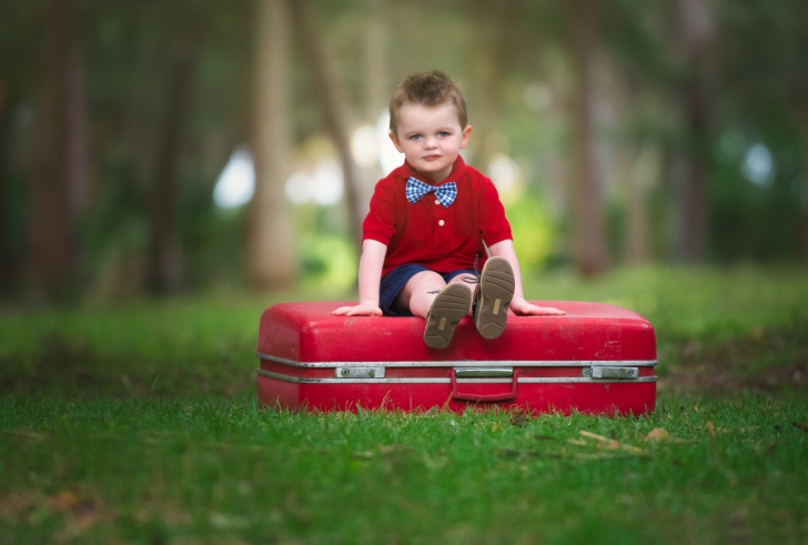 Cute Boy Sitting On Red Luggage wallpaper