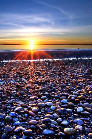 Обои Beach Pebbles In Sun Lights At Sunrise 320x480