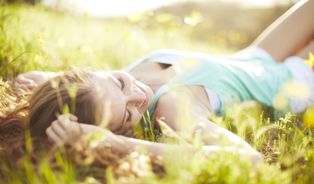 Das Happy Girl Lying In Grass In Sunlight Wallpaper 1024x600