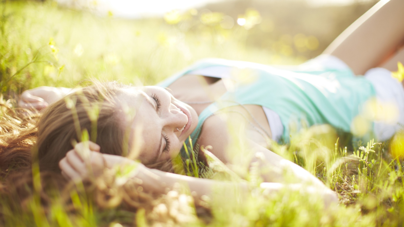 Das Happy Girl Lying In Grass In Sunlight Wallpaper 1366x768