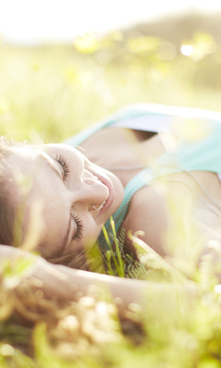 Happy Girl Lying In Grass In Sunlight wallpaper 768x1280