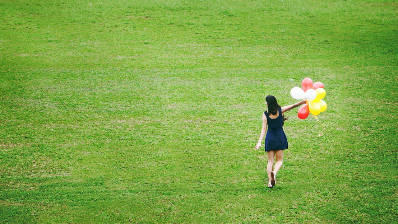 Fondo de pantalla Girl With Colorful Balloons In Green Field 1280x720