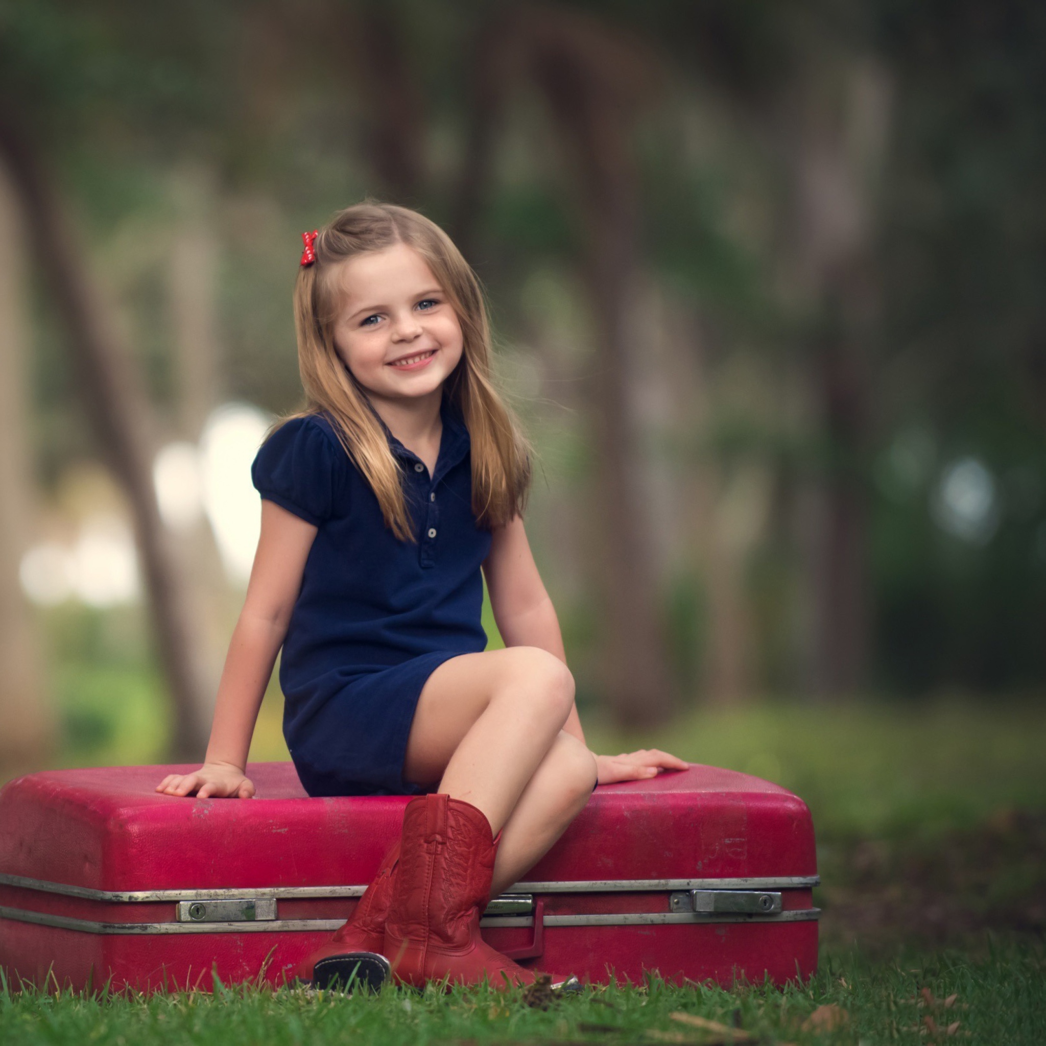 Обои Little Girl Sitting On Red Suitcase 2048x2048