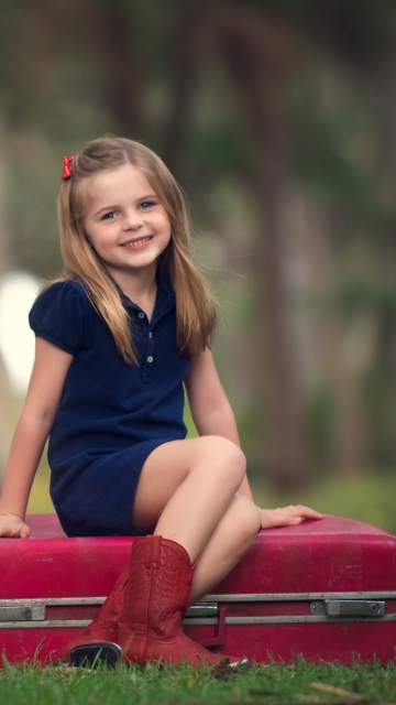 Sfondi Little Girl Sitting On Red Suitcase 360x640