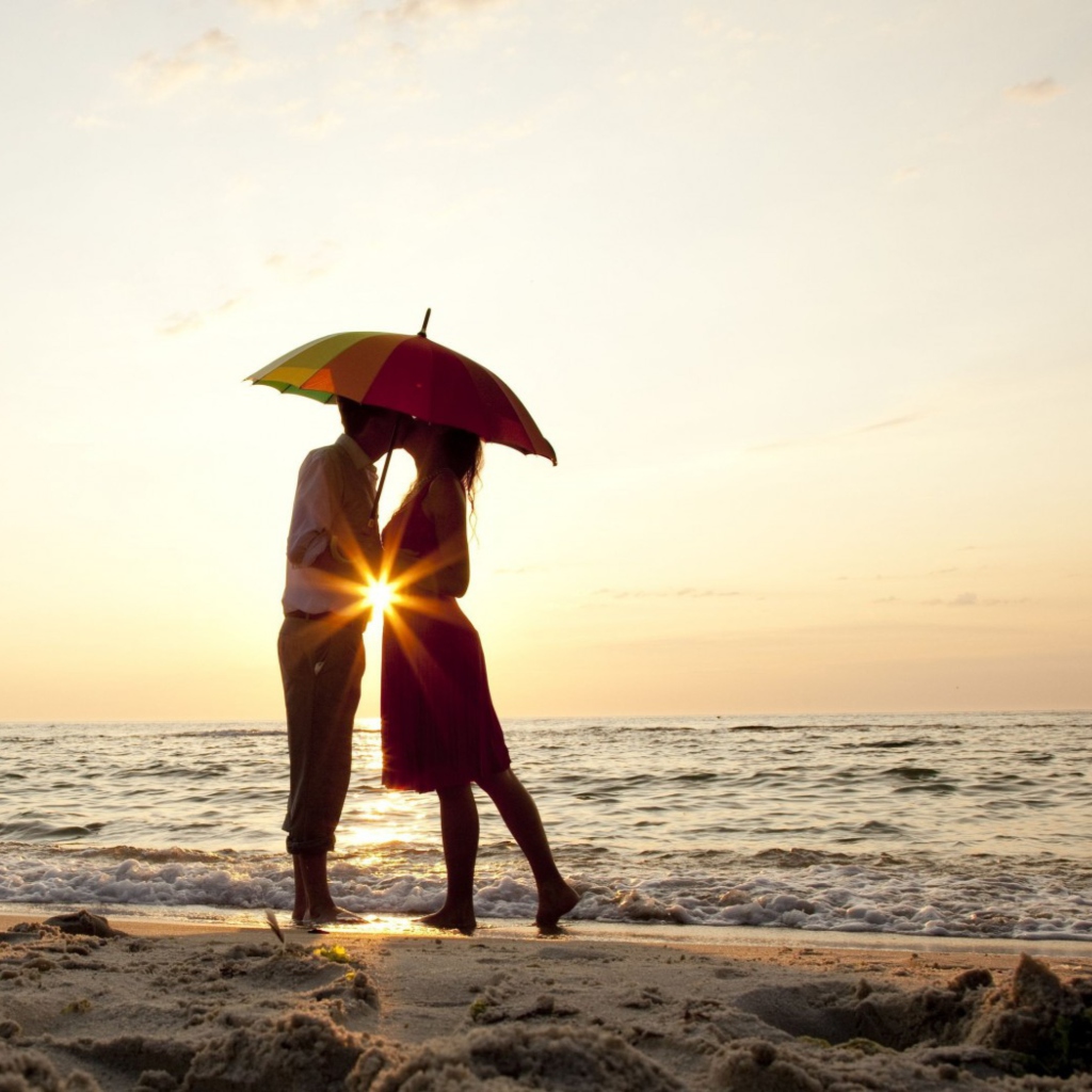 Das Couple Kissing Under Umbrella At Sunset On Beach Wallpaper 1024x1024