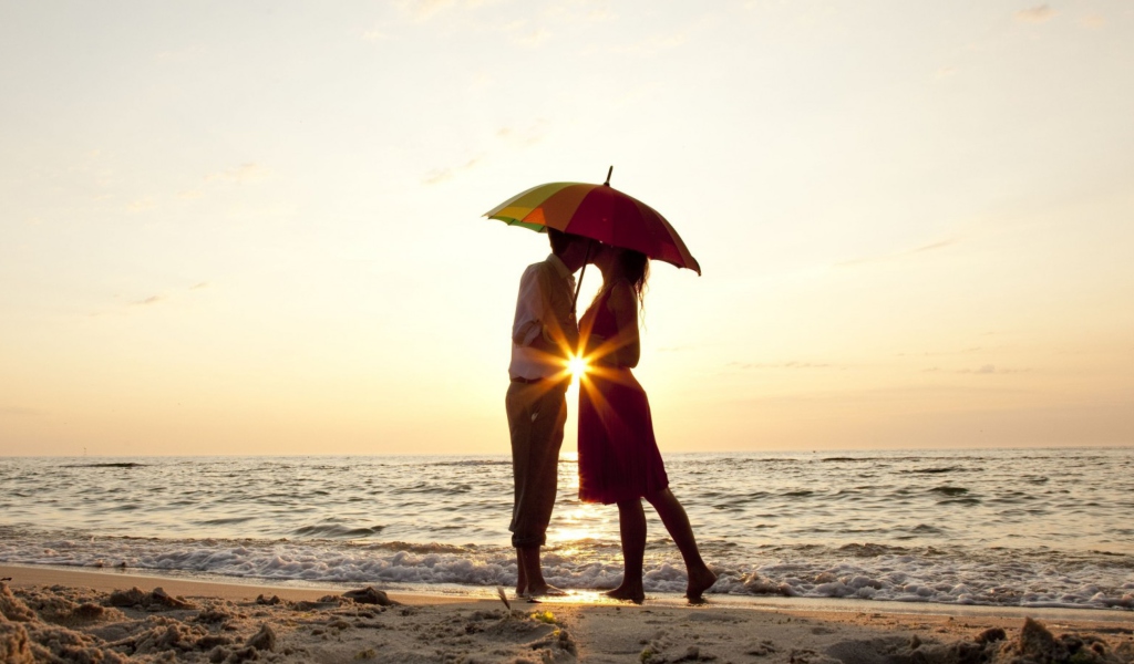 Couple Kissing Under Umbrella At Sunset On Beach wallpaper 1024x600