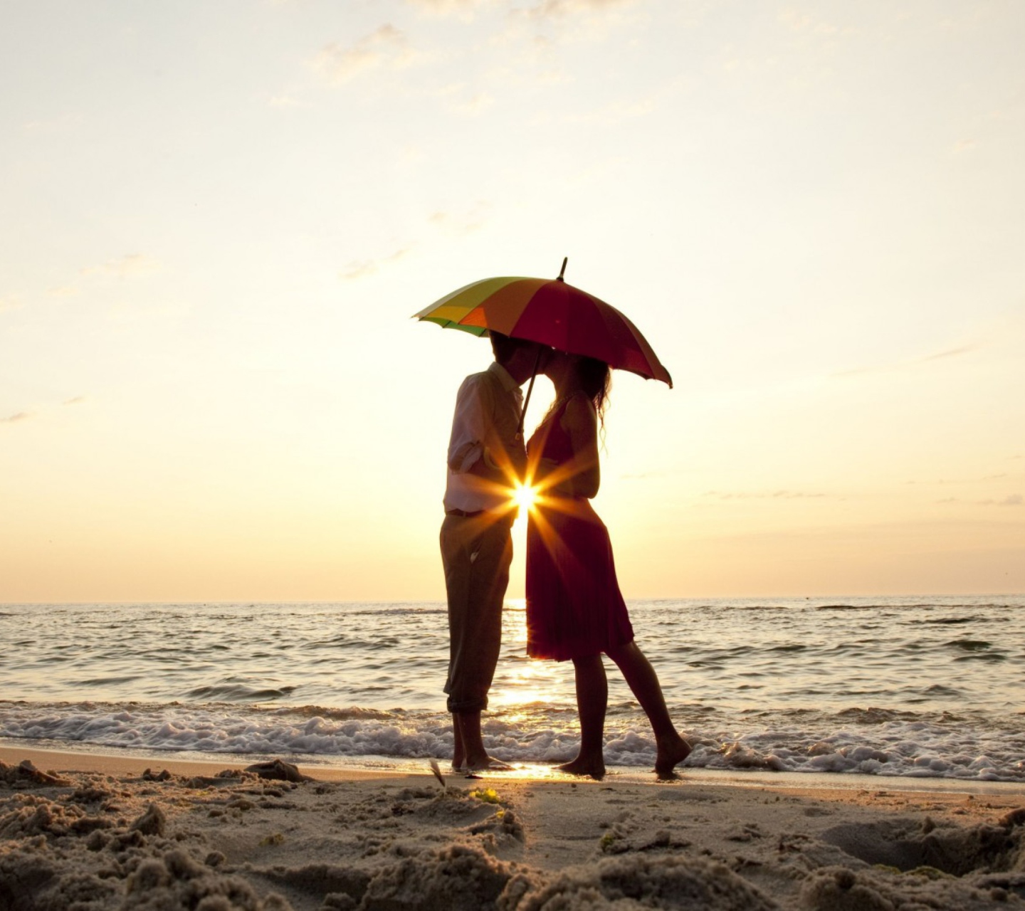 Fondo de pantalla Couple Kissing Under Umbrella At Sunset On Beach 1440x1280
