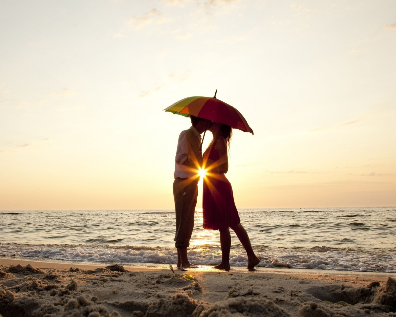 Couple Kissing Under Umbrella At Sunset On Beach wallpaper 1600x1280