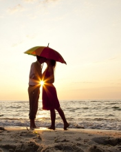 Das Couple Kissing Under Umbrella At Sunset On Beach Wallpaper 176x220