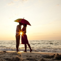 Das Couple Kissing Under Umbrella At Sunset On Beach Wallpaper 208x208