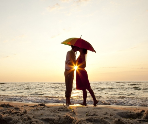 Fondo de pantalla Couple Kissing Under Umbrella At Sunset On Beach 480x400