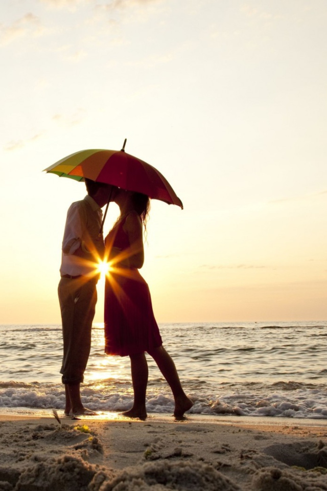 Das Couple Kissing Under Umbrella At Sunset On Beach Wallpaper 640x960