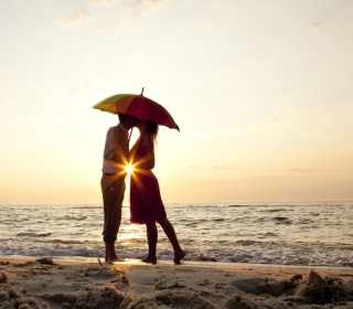 Couple Kissing Under Umbrella At Sunset On Beach - Obrázkek zdarma pro 128x128