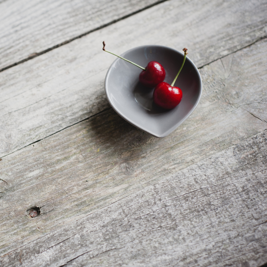 Two Red Cherries On Plate On Wooden Table wallpaper 1024x1024