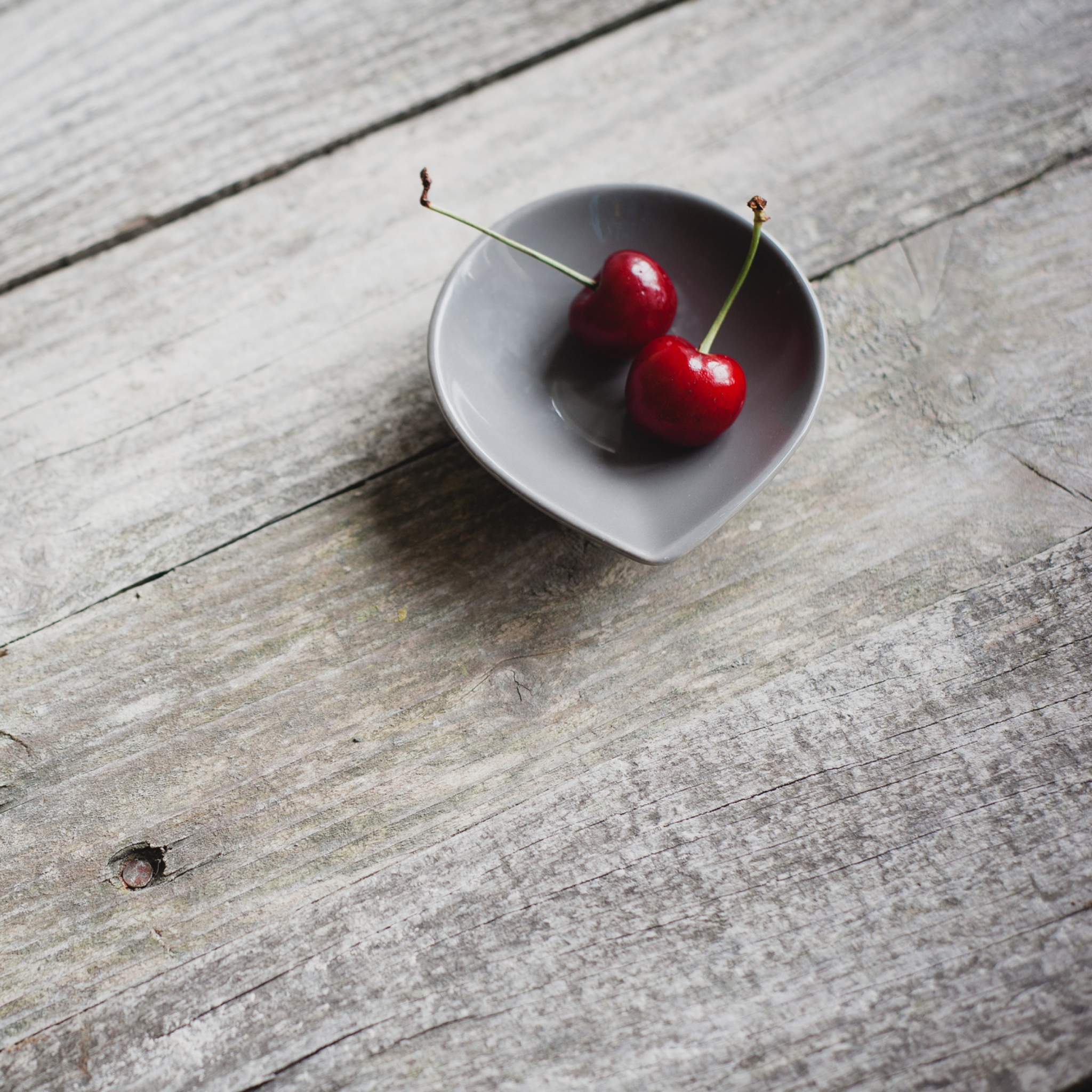 Two Red Cherries On Plate On Wooden Table wallpaper 2048x2048