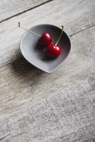 Sfondi Two Red Cherries On Plate On Wooden Table 320x480