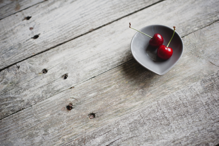 Two Red Cherries On Plate On Wooden Table wallpaper