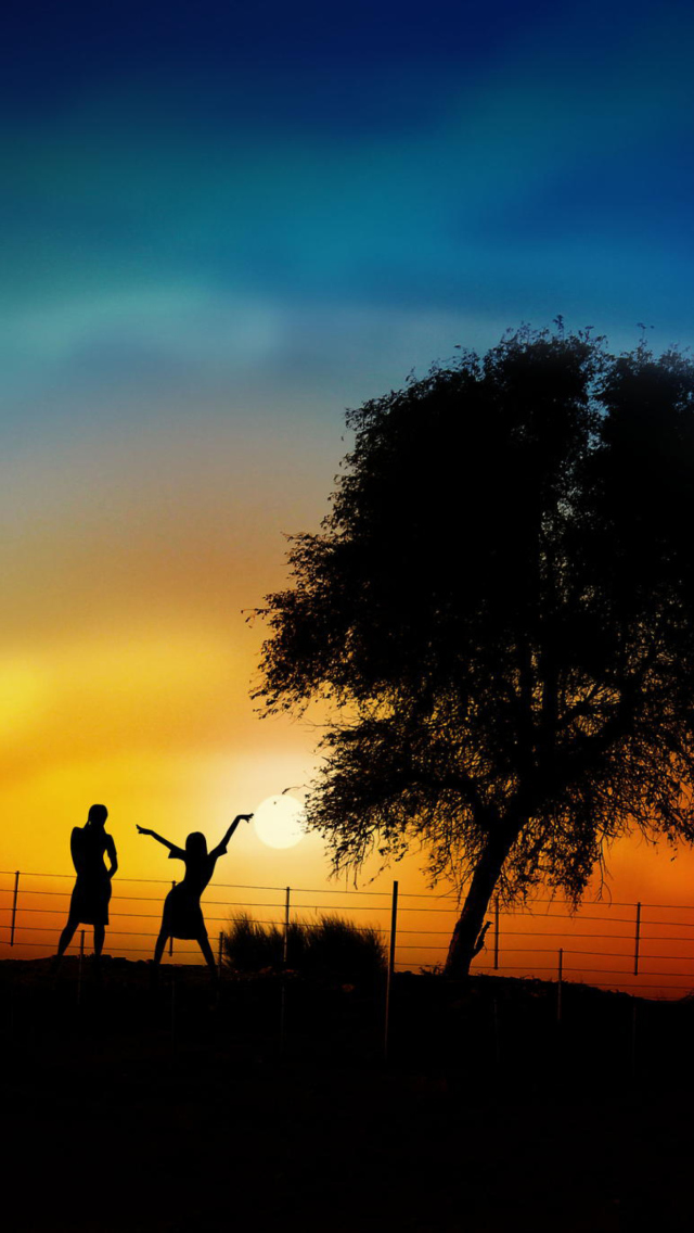 Das Couple Silhouettes Under Tree At Sunset Wallpaper 640x1136