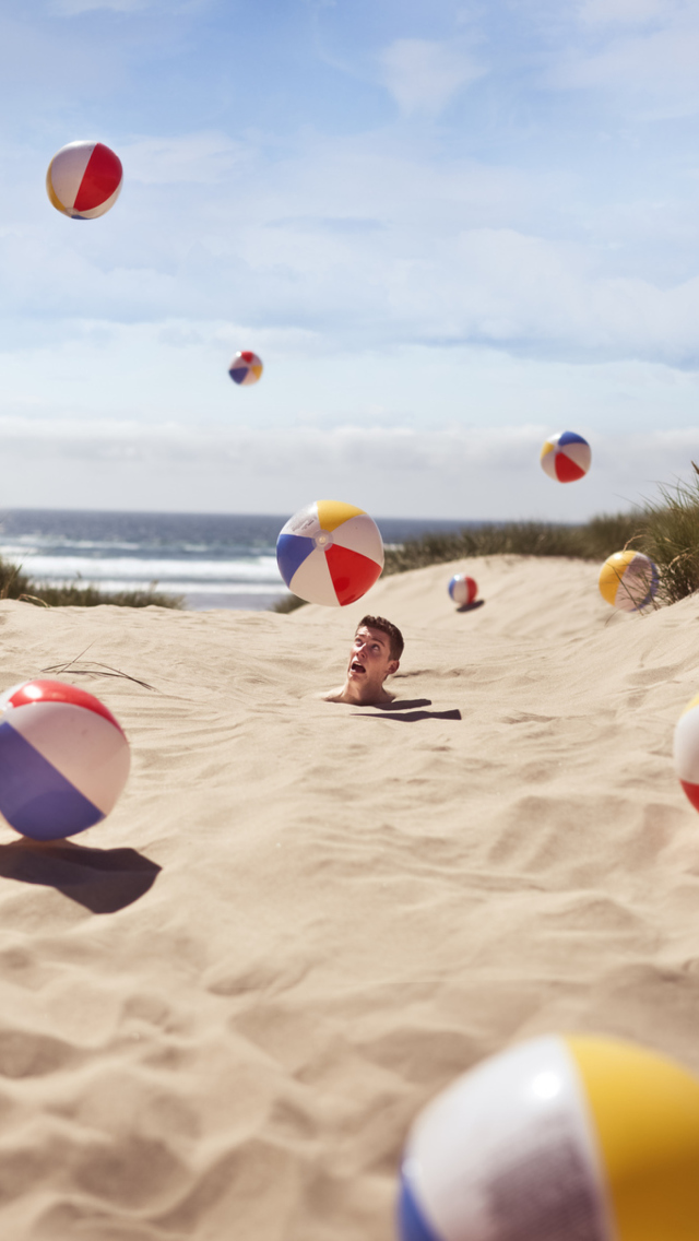 Sfondi Beach Balls And Man's Head In Sand 640x1136