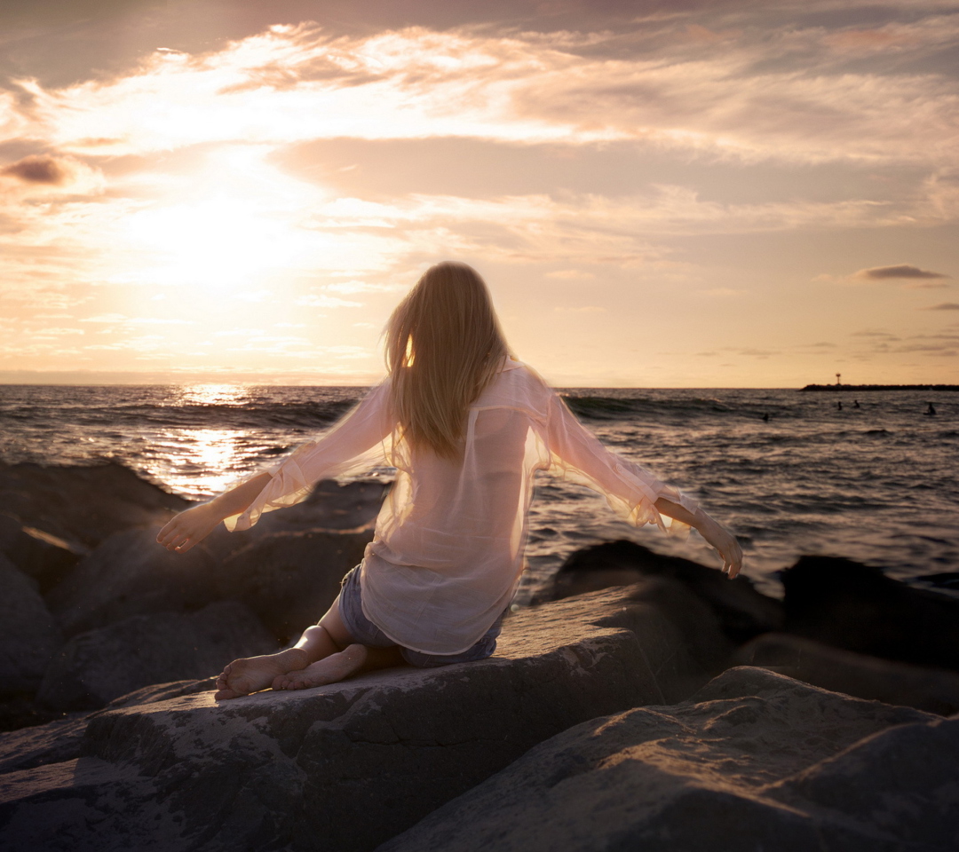 Das Girl Sitting On Stones On Sea Coast Wallpaper 1080x960