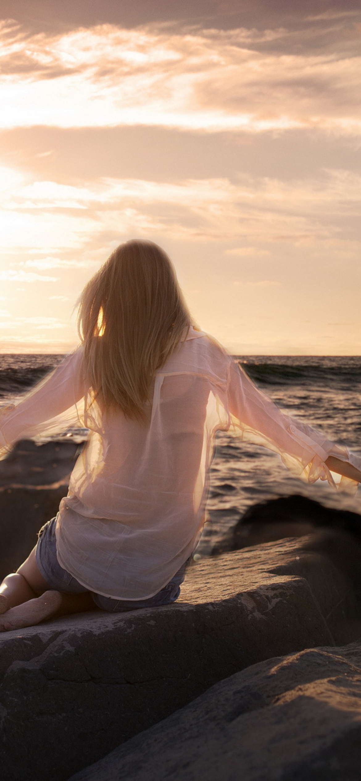 Girl Sitting On Stones On Sea Coast wallpaper 1170x2532