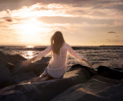 Sfondi Girl Sitting On Stones On Sea Coast 176x144