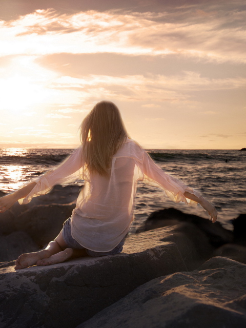 Fondo de pantalla Girl Sitting On Stones On Sea Coast 480x640