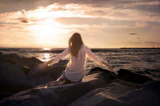 Girl Sitting On Stones On Sea Coast - Obrázkek zdarma 