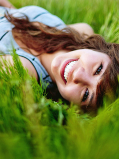 Smiling Girl Lying In Green Grass wallpaper 240x320