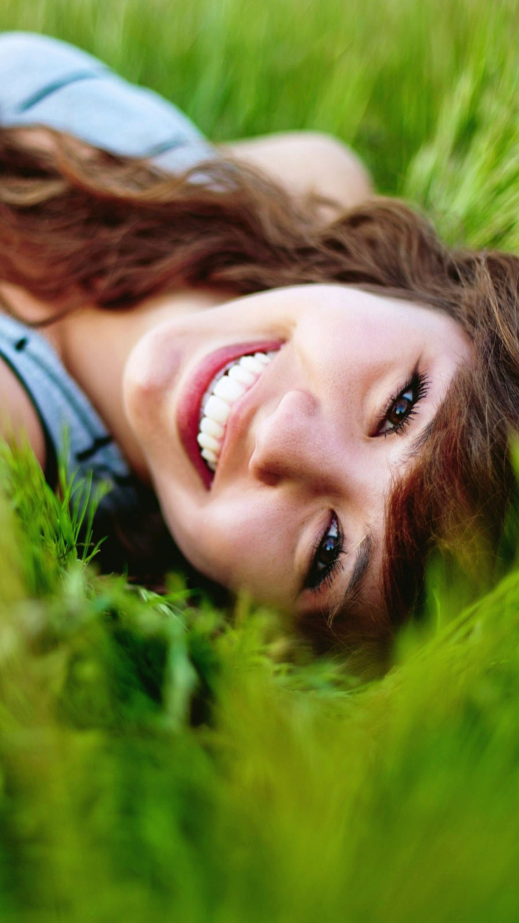 Smiling Girl Lying In Green Grass wallpaper 750x1334