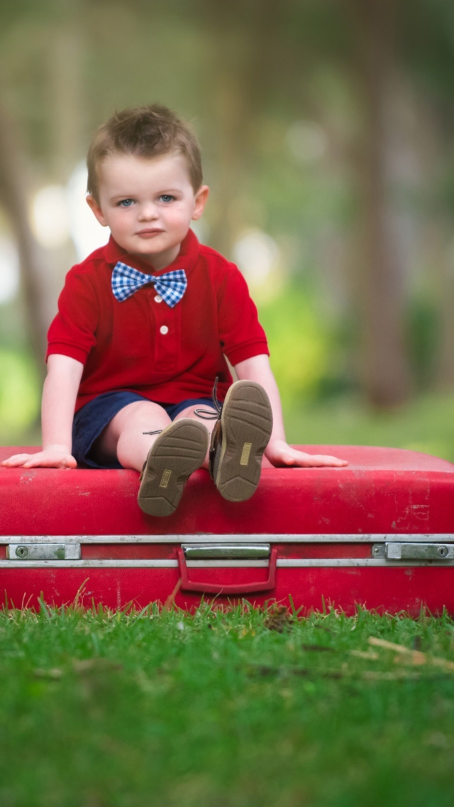 Cute Boy Sitting On Red Luggage wallpaper 640x1136