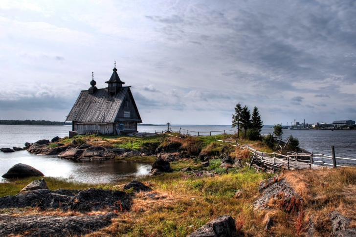 Old small house on the rocky river shore wallpaper