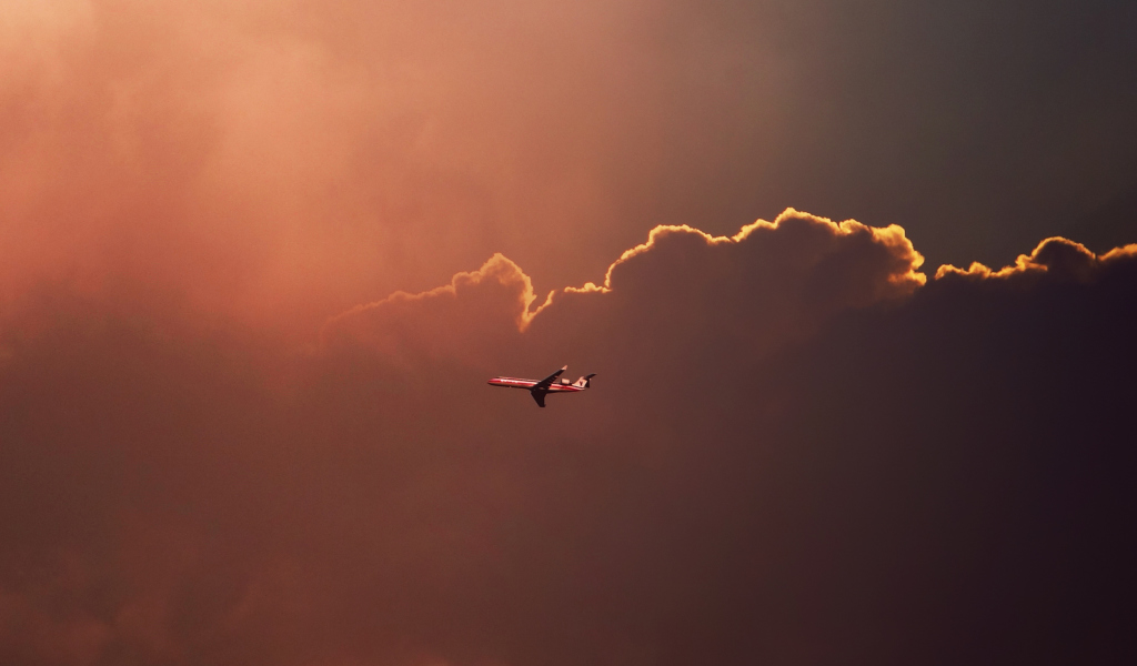 Airplane In Red Sky Above Clouds wallpaper 1024x600