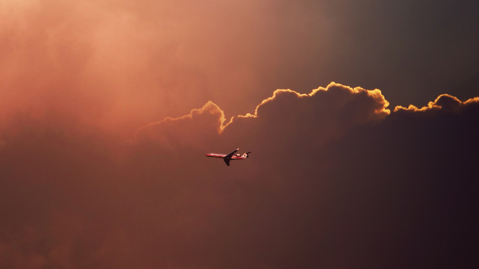 Обои Airplane In Red Sky Above Clouds 1920x1080