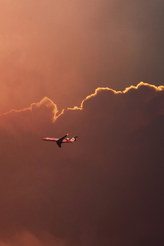 Das Airplane In Red Sky Above Clouds Wallpaper 320x480