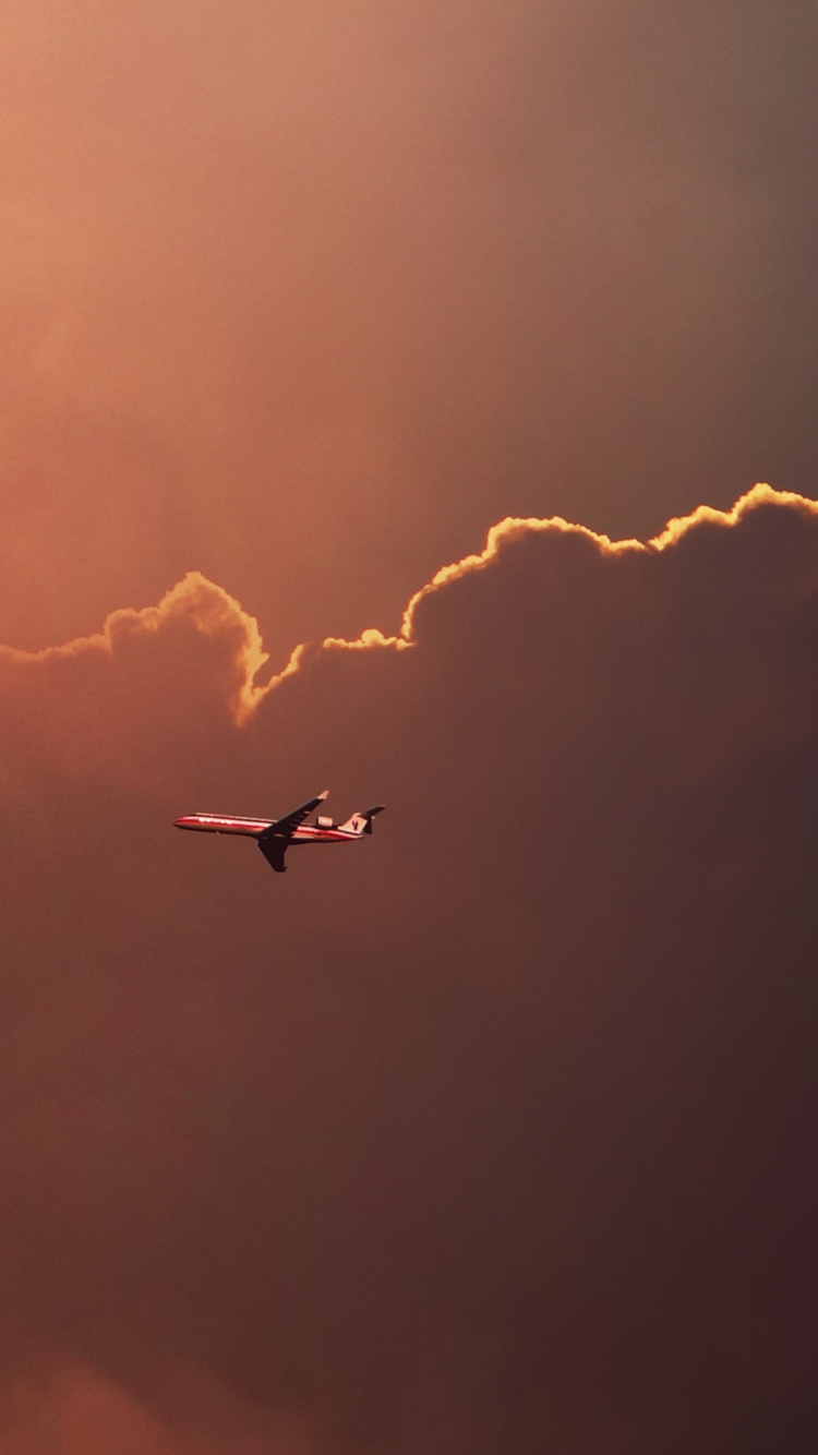 Fondo de pantalla Airplane In Red Sky Above Clouds 750x1334